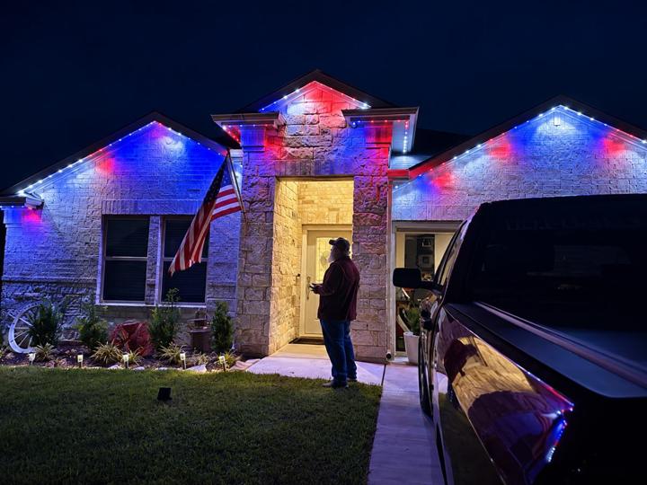 Red, white and blue 4th of July lighting on a stone home with an American flag