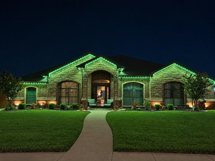 Green holiday lighting on a stone and brick home