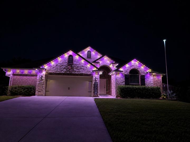 Game day purple lighting on a stone and brick home