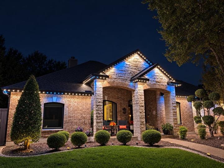 Blue game day lighting on a brick and stone home