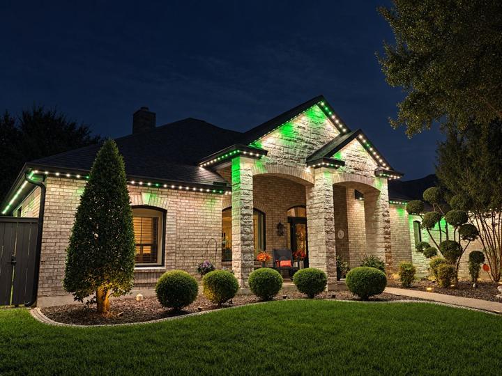 Green game day lighting on a brick and stone home