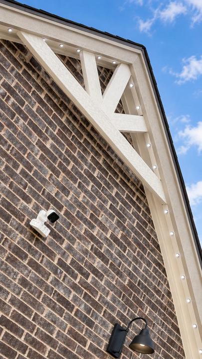 Lights set into the trim along a white gable with a security camera