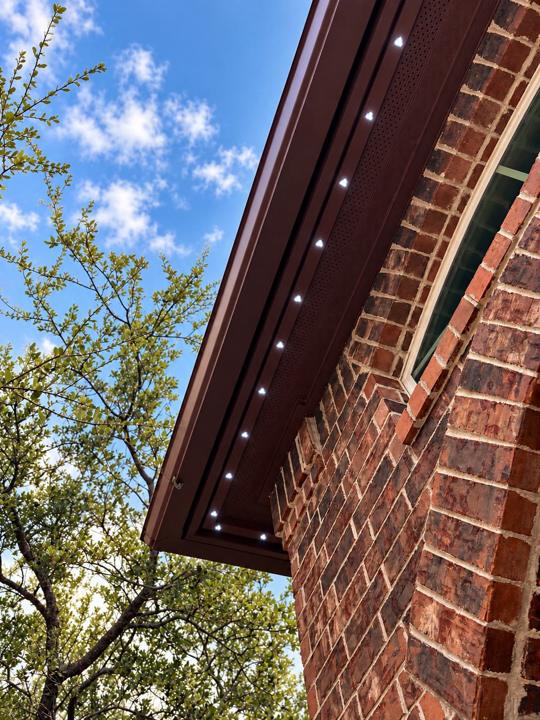 Lighting track color-matched to a brown soffit on a red brick home