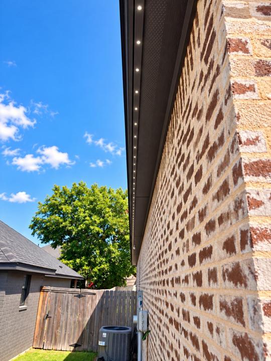 Row of recessed lights along the soffit of a brick home